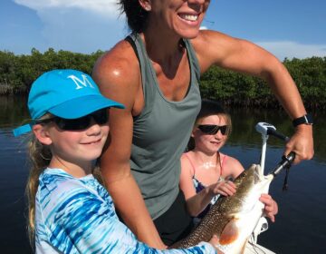 A mother and children holding up a fish they caught on a fishing charter boar in Crystal River, FL.